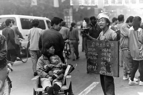 小饭馆伙计胸挂菜谱，当街吆喝生意.jpg